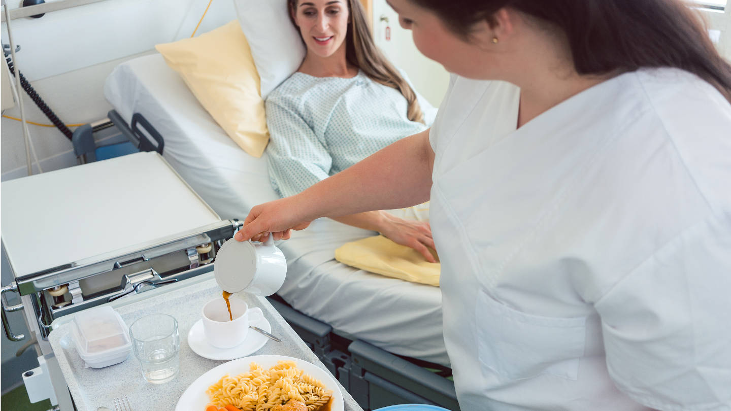 Nurse Serving Food In The Hospital To A Patient In Bed, Top View